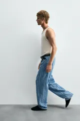 Pantalón de jean azul con rayas verticales texturadas, corte relaxed fit, cinco bolsillos, efecto lavado y cierre frontal con cremallera y botón.