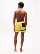 Short de baño amarillo de Tommy Hilfiger, con cintura elástica negra, cordón blanco y logo de la marca en la pierna izquierda.