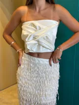 Top strapless color blanco, con diseño drapeado y nudo central.