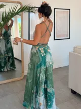 Vestido largo de tela fluida, color verde esmeralda con estampado abstracto en tonos turquesa y detalles dorados. Diseño asimétrico con un solo tirante tejido en el hombro.