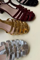 Sandalia de cuero acharolado negro con puntera calada y pulsera ajustable.