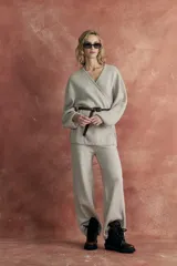 Conjunto de punto color beige, compuesto por un sweater cruzado con cinturón fino marrón y un pantalón de corte recto.