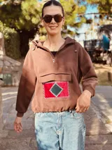 Canguro color chocolate de algodón con cierre parcial en el cuello y bolsillo frontal con apliques geométricos bordados a mano en terciopelo rojo y verde.