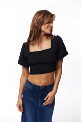 Top corto negro con escote cuadrado, mangas cortas abullonadas y corte ajustado.