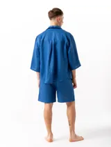 Camisa azul de lino con mangas 3/4, un bolsillo en el lado izquierdo y un pliegue en la espalda.