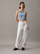Top corto de denim rígido de algodón celeste, con cuello alto, espalda abierta con cierre anudado y logo de Calvin Klein en el bajo.