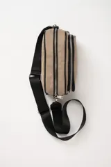 Bandolera rectangular color beige con tres compartimentos con cierre y correa larga negra regulable.