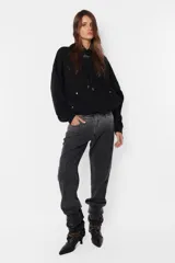 Buzo hoodie negro de frisa, corte oversize, con puños y cintura de rib al tono, capucha forrada y bolsillo canguro. Detalle de remaches en la boca del bolsillo, cierre metálico niquelado en el puño de las mangas, cordones con ojalillos y punteras personalizadas de marca. Cordones atracados en delantero con bordado de marca.