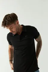 Remera polo negra de manga corta con cuello clásico, cierre de botones, bolsillo en el pecho y logo estampado.