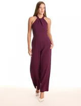 Enterito largo de crepe color rojo, con escote halter anudado y pierna ancha. Presenta bolsillos delanteros y abertura en la espalda con cierre invisible y botón.