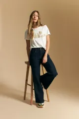 Remera de manga corta color negro con cuello redondo y un aplique bordado de flores y hojas en color beige claro en el centro del pecho.