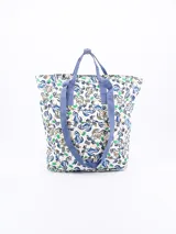 Mochila con estampado de dinosaurios y palmeras sobre fondo blanco, con asas de tela azul.