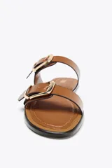 Sandalias planas color marrón con doble tira y hebillas doradas.