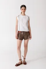 Blusa color ladrillo de lino 100% con cuello redondo y sin mangas. Presenta vivos y pespuntes a contratono en color marrón.