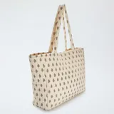 Bolso shopper acolchado color crema con estampado floral en tonos rosa y negro.