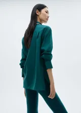 Camisa de vestir verde esmeralda de corte recto, con cuello camisero, cierre frontal con botones ocultos y mangas largas con puños abotonados.