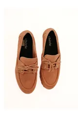 Mocasín de cuero gamuzado color marrón claro, con lazo frontal y suela antideslizante.