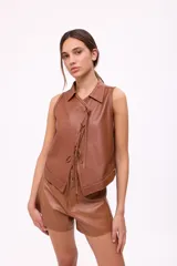 Top color camel de cuero, con cuello camisero, sin mangas y cierre frontal con lazos.