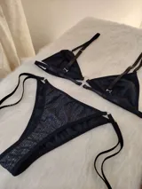 Conjunto de bikini negro con destellos verticales multicolor. El corpiño es de corte triangular con breteles finos regulables y aro metálico en el centro. La bombacha es tipo colaless con tiras laterales regulables.