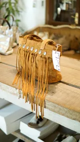 Cartera de cuero color tostado con flecos y tachas plateadas.