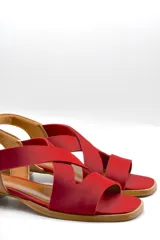 Sandalias bajas color beige con tiras cruzadas y elástico dorado en el talón.