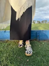 Zapatillas bajas con estampado animal print de vaca en blanco y negro, con cordones marrones y suela color caramelo.