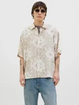 Camisa de manga corta con estampado de cachemira en tonos beige y blanco, cuello resort y cierre de botones. Confeccionada en tejido plano con mezcla de algodón y lino, de corte amplio.