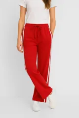 Pantalón deportivo rojo de corte recto, con cintura elástica ajustable con cordón y rayas blancas verticales en los laterales.