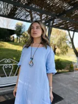 Vestido celeste de lino, corte oversize, con mangas cortas y bolsillos laterales.