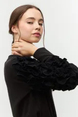 Remera negra de punto con mangas largas abullonadas con volantes.