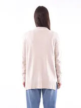Saco color beige de tejido de punto, con cuello abierto, bolsillos frontales y mangas largas con detalle de botones en los puños.