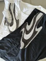 Remera de algodón color negro con bordado a un costado en diseño artístico.