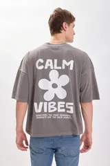 Remera gris con estampa en la espalda que dice "Calm Vibes" con una flor en el medio. Corte amplio y recto, con proporciones cuadradas.
