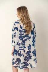 Camisa larga de color blanco con estampado de flores azules, cuello en V y mangas largas.