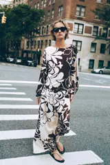 Pantalón de tiro alto con delantero cruzado y broche, con estampado floral en tonos marrones sobre fondo crudo.