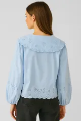Camisa celeste de algodón con bordados florales, cuello babero con volados y lazo.