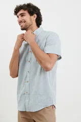 Camisa celeste de manga corta con cuello abotonado y bolsillo en el pecho.