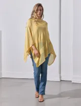 Poncho blanco de tejido calado con lurex, terminación asimétrica y cuello redondo.