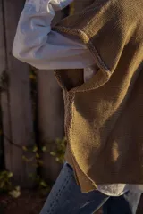 Chaleco tejido color tostado con apliques de cuero marrón en el cuello y detalle de pespunte en el contorno.