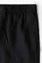 Pantalón negro de lino con corte recto, cintura elastizada con cordón ajustable, bolsillos laterales y bolsillo trasero.