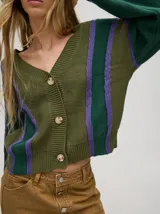 Cardigan corto de punto color verde oliva con rayas verticales en verde oscuro y lila. Tiene escote en V, mangas largas y botones al frente.