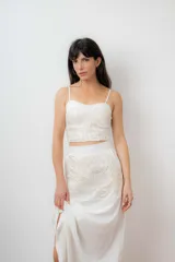 Conjunto de top corto y falda midi color blanco, con bordado artesanal de diseño orgánico. El top tiene breteles finos regulables y la falda tiene tajo lateral.