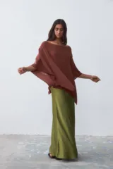 Poncho tejido color ladrillo con brillo, de corte asimétrico y cuello bote.