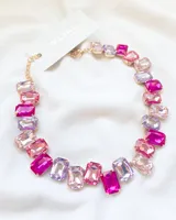 Collar de fiesta con piedras en tonos rosados y lilas, con cadena dorada.