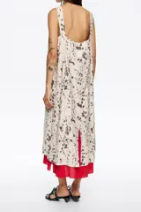 Vestido midi de corte recto, sin mangas y escote cuadrado, con estampado moteado en tonos marrón oscuro sobre fondo beige claro. Lleva un forro o capa inferior de color rojo vibrante que asoma en el ruedo.