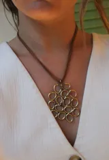 Collar con colgante dorado formado por aros entrelazados, con cordón marrón.