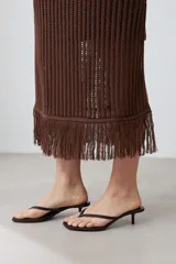 Vestido marrón de tejido calado, corte recto, largo midi, sin mangas y con flecos en el ruedo.