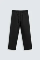 Pantalón de lino color marrón oscuro, de corte recto y relaxed fit. Tiene cintura elástica ajustable con cordón, bolsillos frontales y traseros de parche.