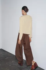 Camisa color beige de algodón con escote en V y volantes. Tiene mangas largas con botón en los puños y cierre con lazos en el frente.