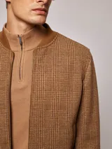 Campera bomber marrón con estampado a cuadros, cuello, puños y ruedo acanalados. Cierre frontal con cremallera.